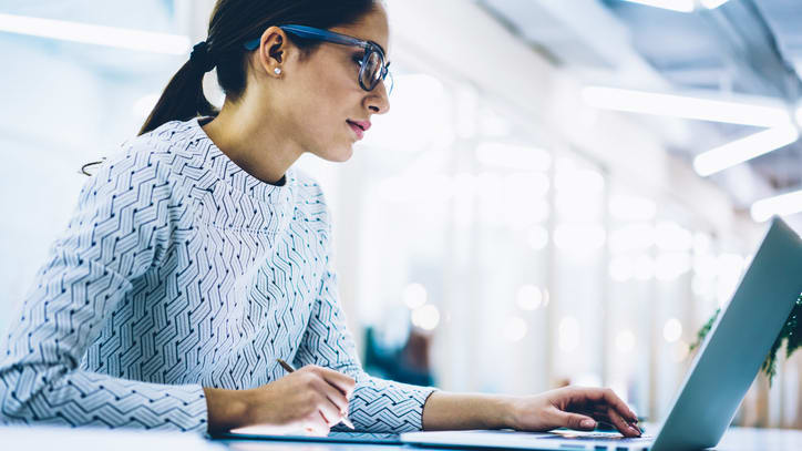 A woman working on a laptop in an office.