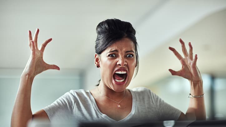 A woman is screaming in front of a computer screen.