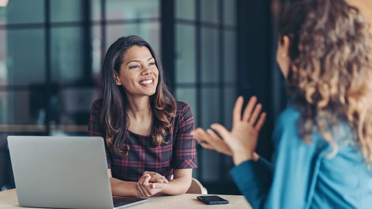 Two women talking at a table in an office.