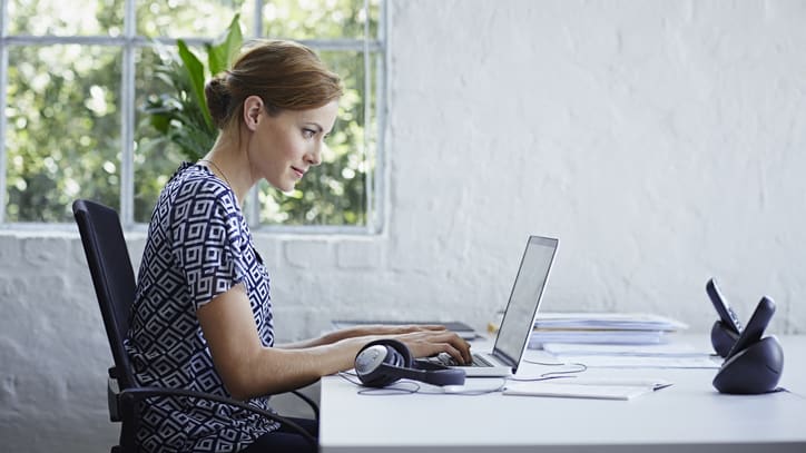 A woman working on a laptop in an office.