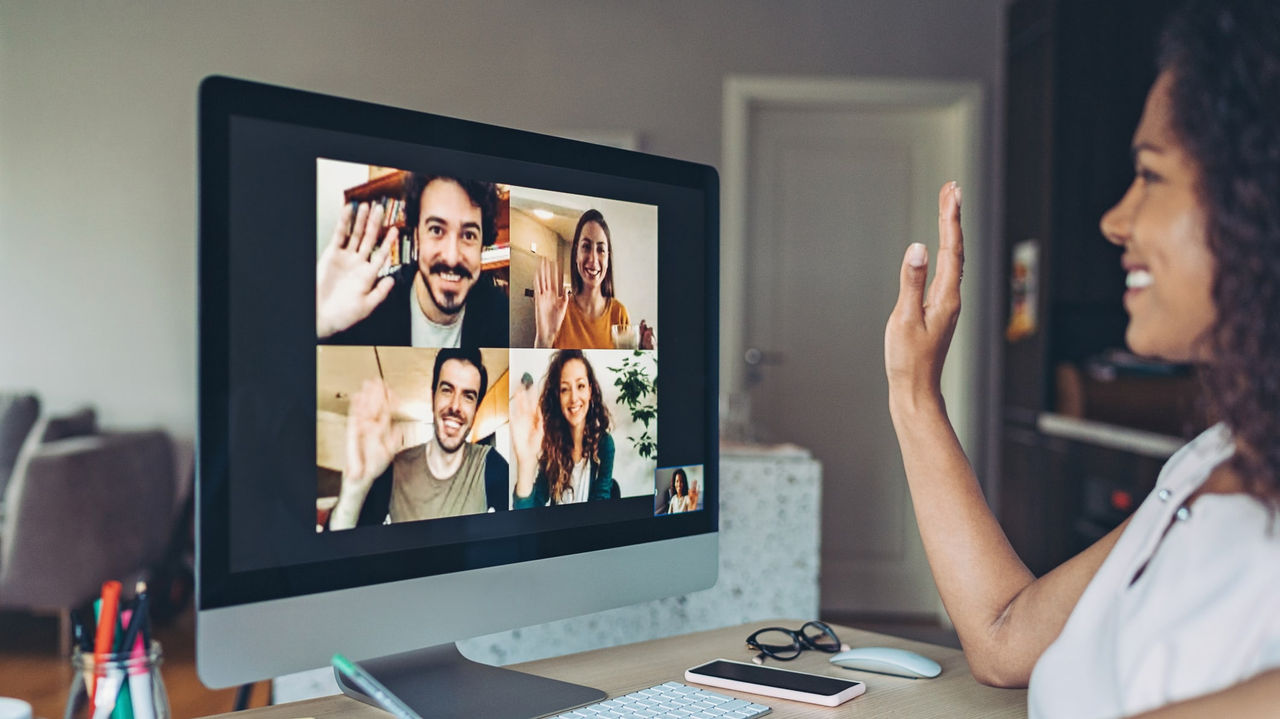 A woman on a computer with a group of people on a video call.