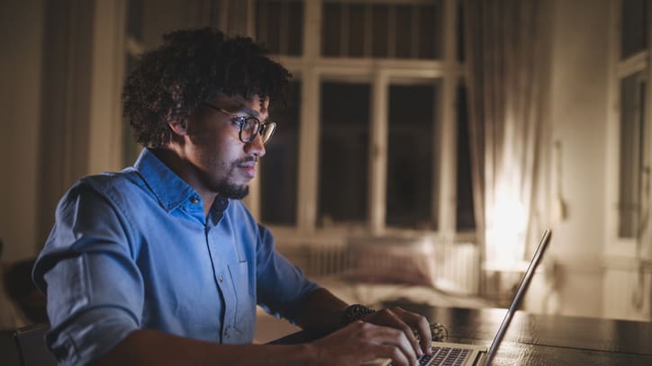 A man working on his laptop at night.