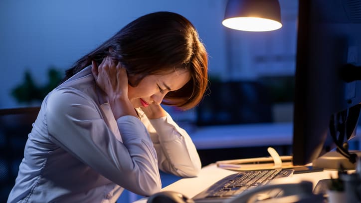 A woman is sitting in front of a computer at night.