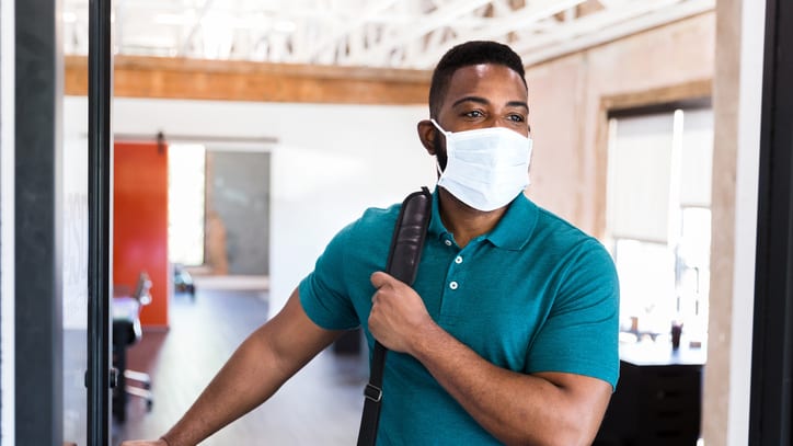 A man wearing a face mask in an office.