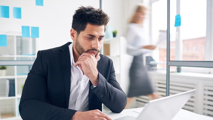 A man sitting at a desk with his hand on his chin.