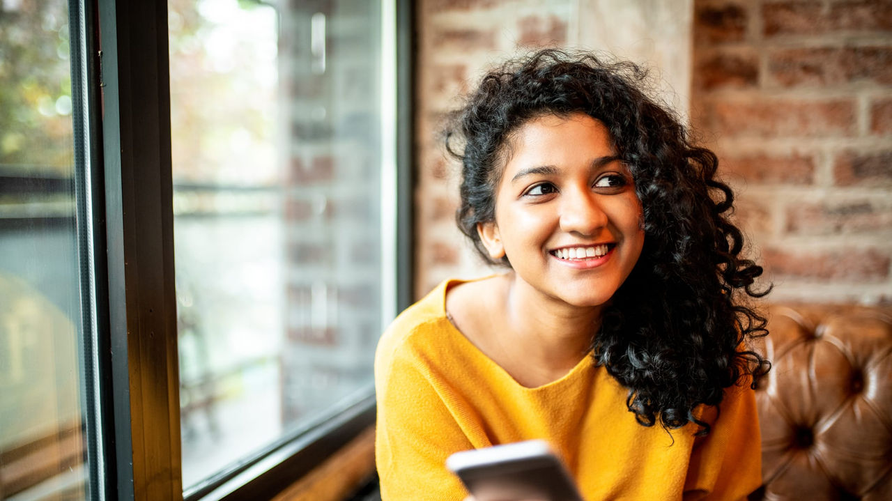 A young woman looking at her phone while sitting in a cafe.