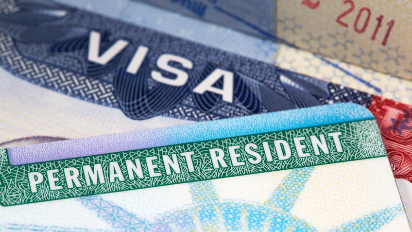 A group of permanent resident visas are stacked on top of each other.