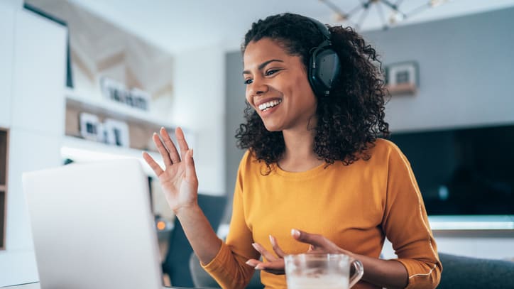 A woman wearing headphones is using a laptop at home.