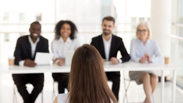 A woman sitting at a table in front of a group of business people.