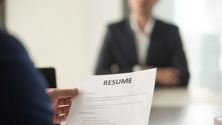 A man is holding a resume in front of a man in a suit.