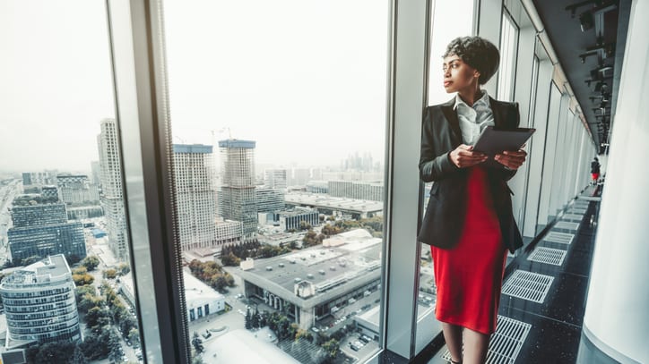 businesswoman standing on a balcony looking at the city.