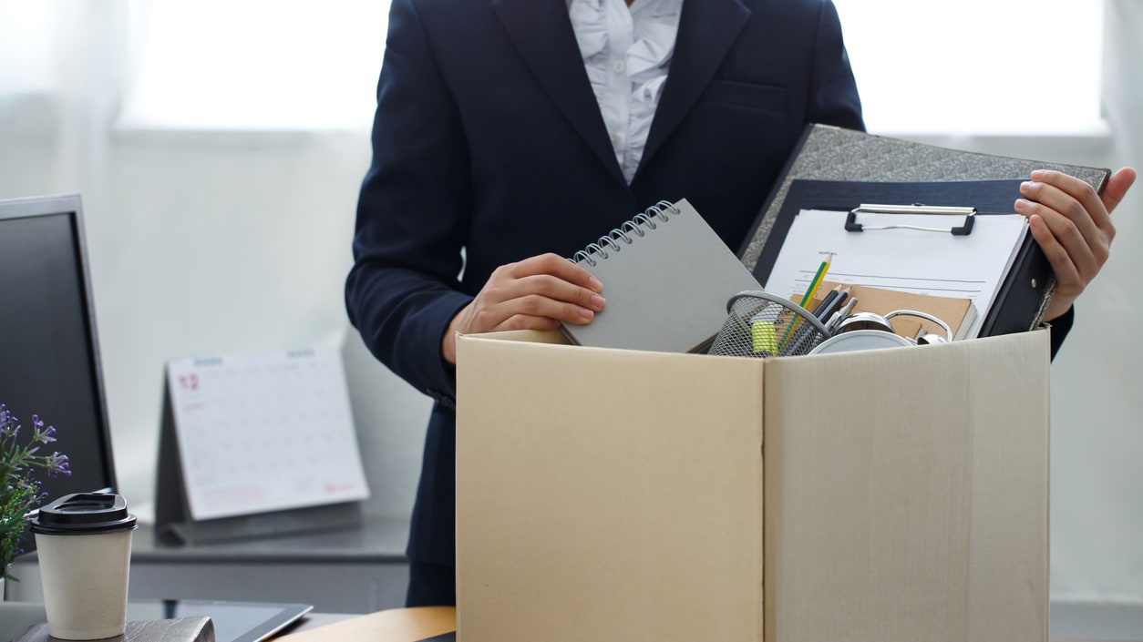 A business woman is opening a cardboard box in her office.