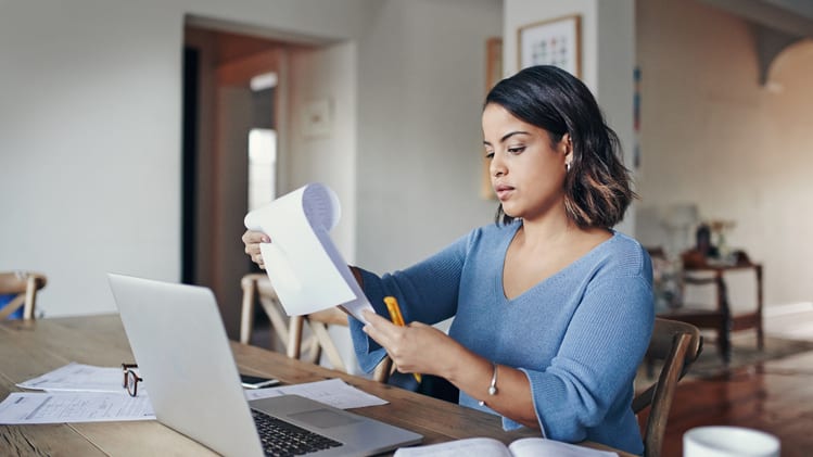 A woman sitting at a table with a laptop and papers.