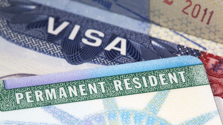 A group of permanent resident visas are stacked on top of each other.