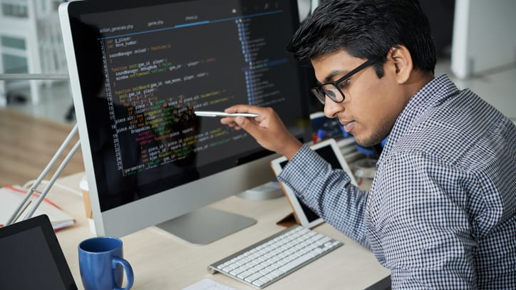 A man working on a computer with code on the screen.