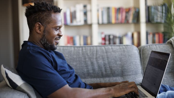 A man sitting on a couch using a laptop.