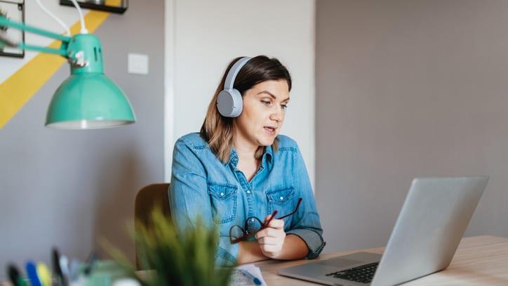 A woman wearing headphones and working on a laptop.