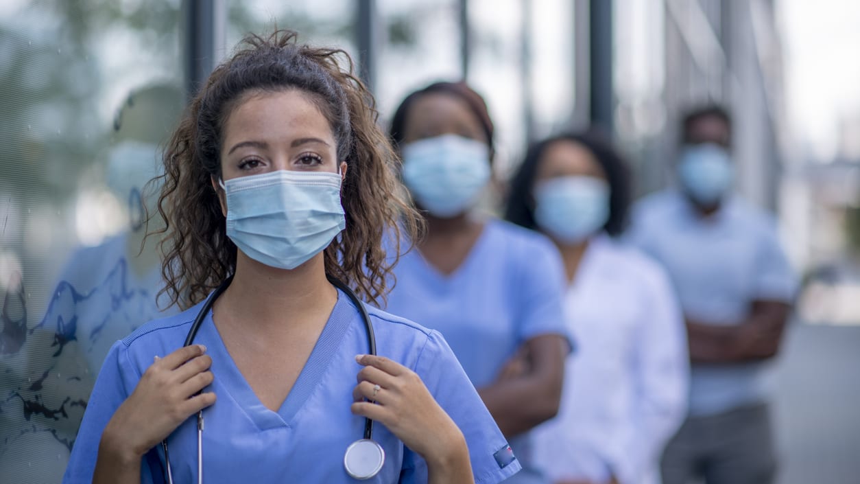 A group of nurses wearing surgical masks in front of a building.