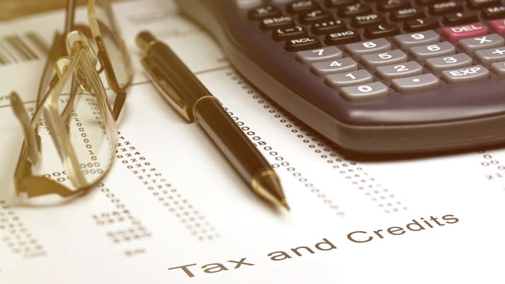 A calculator and glasses sit on top of a tax and credit document.