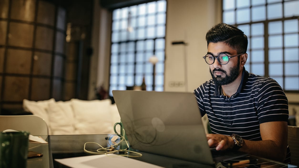 A man working on a laptop in his home office.