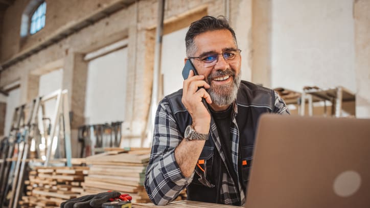 A construction worker talking on the phone in a workshop.