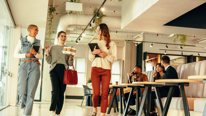 A group of people walking through a cafe.