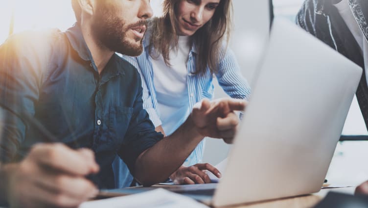 A group of people looking at a laptop.