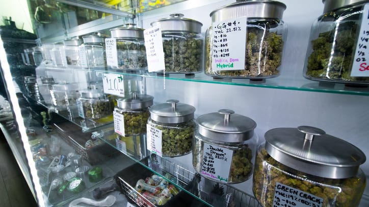 Marijuana in glass jars on shelves in a store.