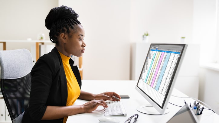 A woman working on a computer with a spreadsheet on it.