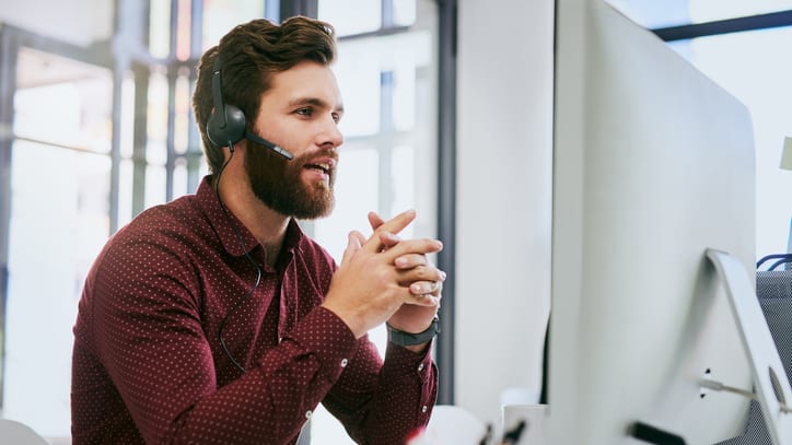 A man wearing a headset in front of a computer.