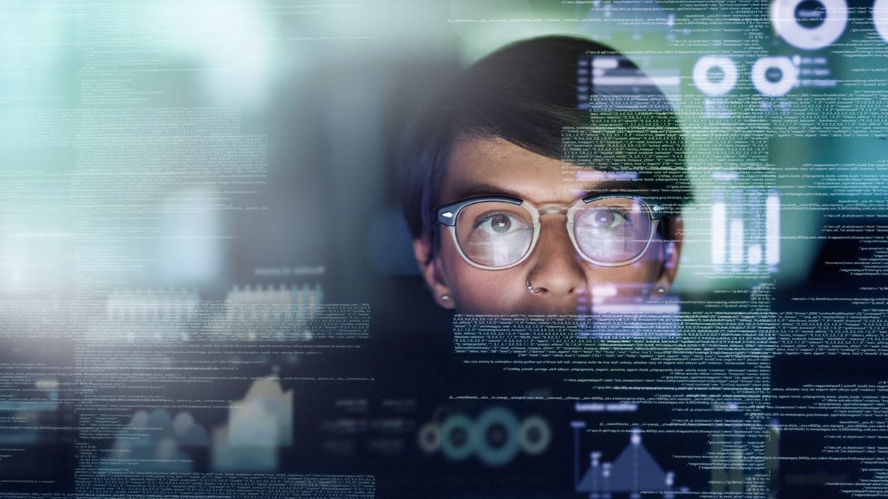 A man in glasses is looking at a computer screen.