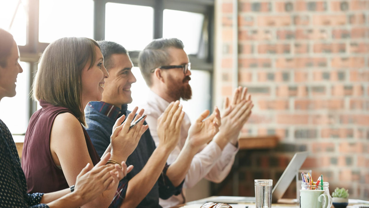 A group of business people clapping at a table.