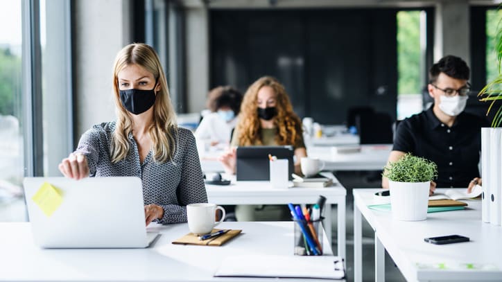 A group of people wearing face masks in an office.