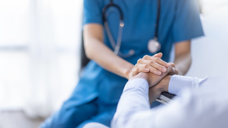 A nurse is holding a patient's hand.