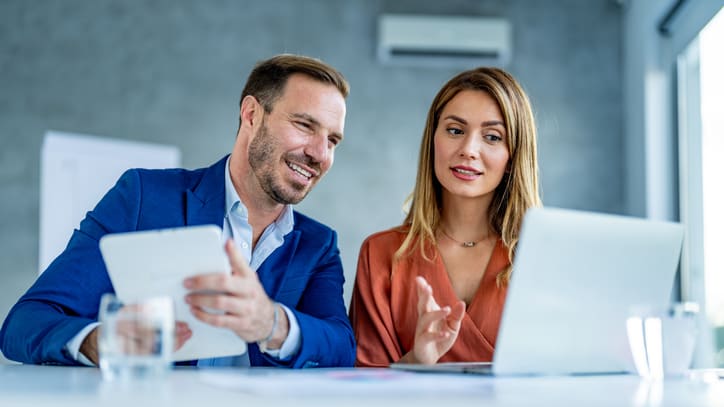 Two business people looking at a laptop in an office.