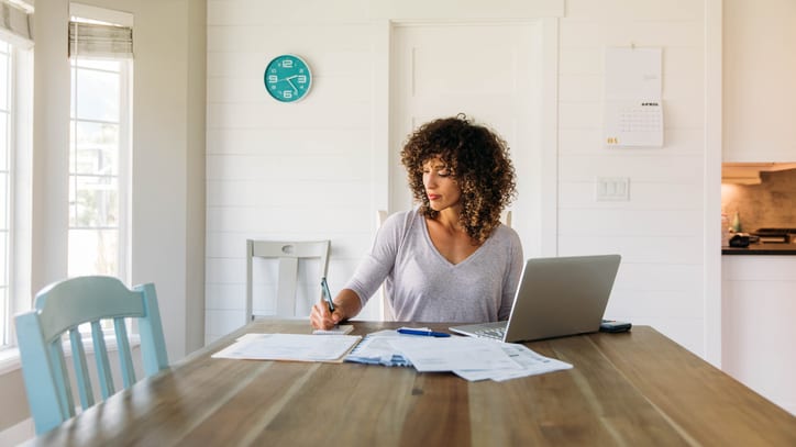 A woman sitting at a table with a laptop and papers.