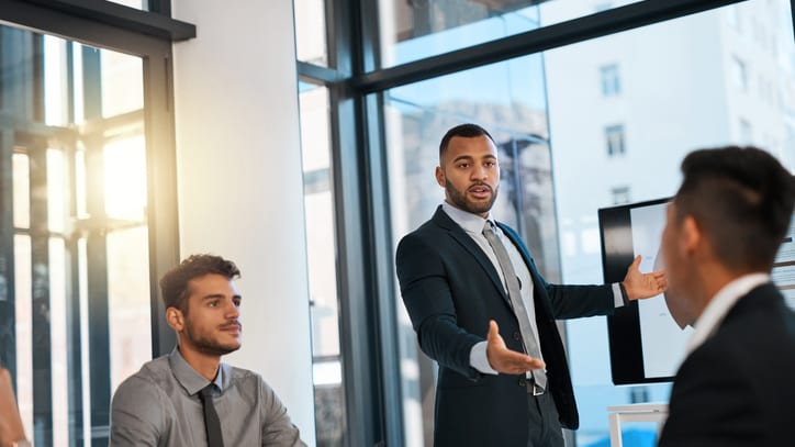 A businessman giving a presentation to a group of people in an office.