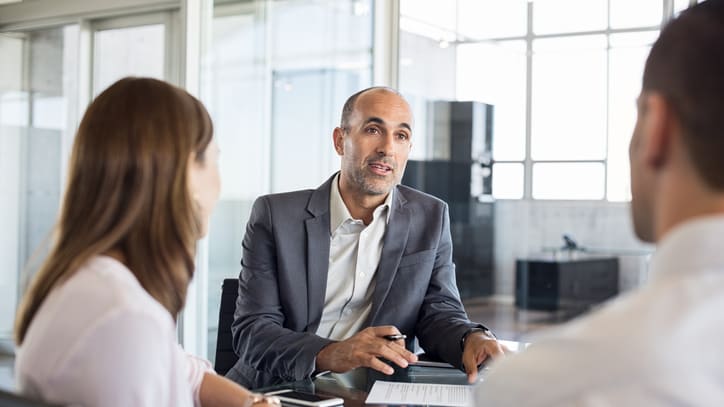 A businessman talking to a woman in an office.