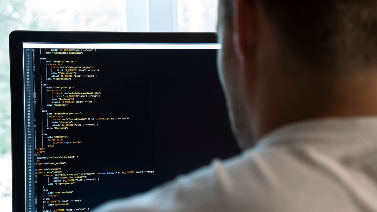 A man is looking at a computer screen with code on it.