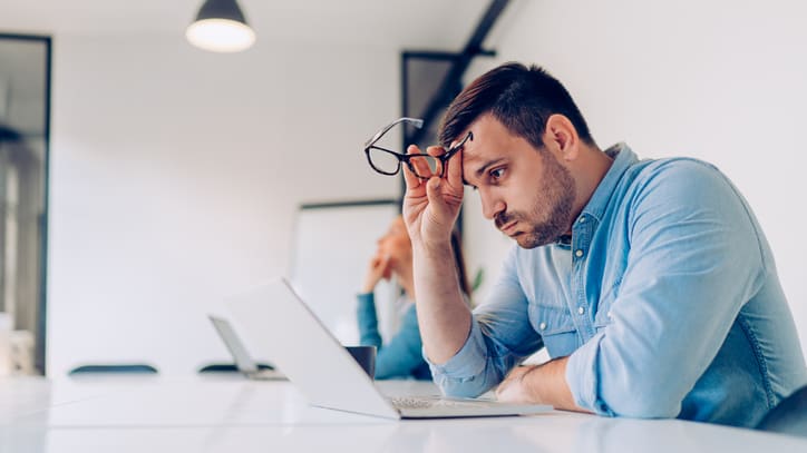 A man is sitting at a table with a laptop in front of him.