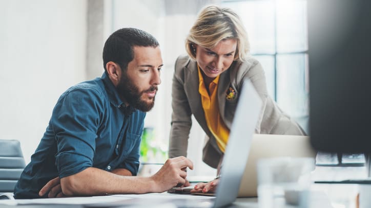 Two business people looking at a laptop in an office.