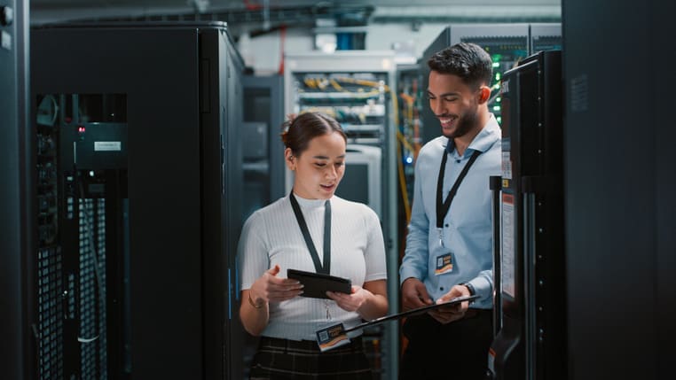 Two people standing in a server room.