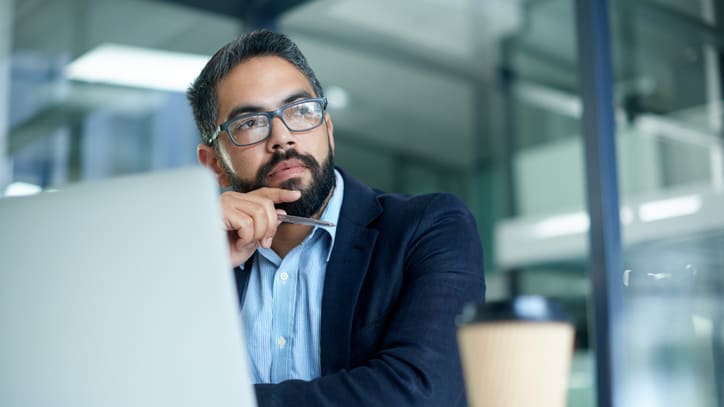 A businessman looking at his laptop in an office.