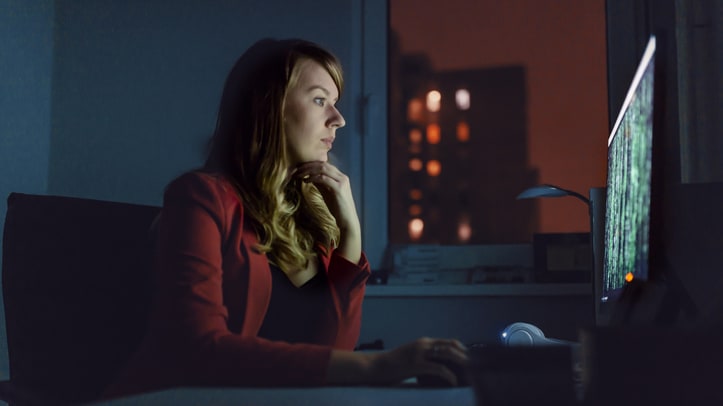 A woman sitting in front of a computer at night.