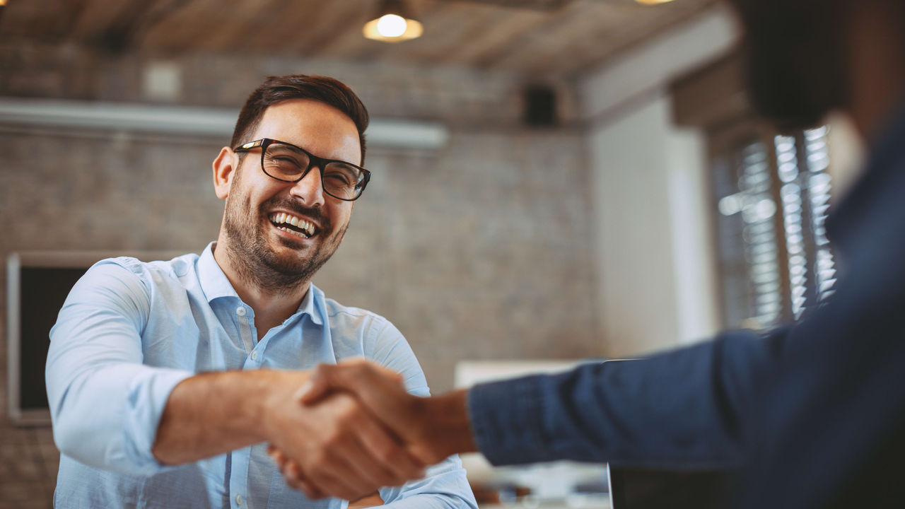 A man shaking hands with another man in an office.