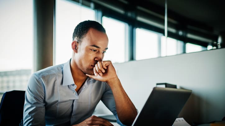 A man working on a laptop in an office.