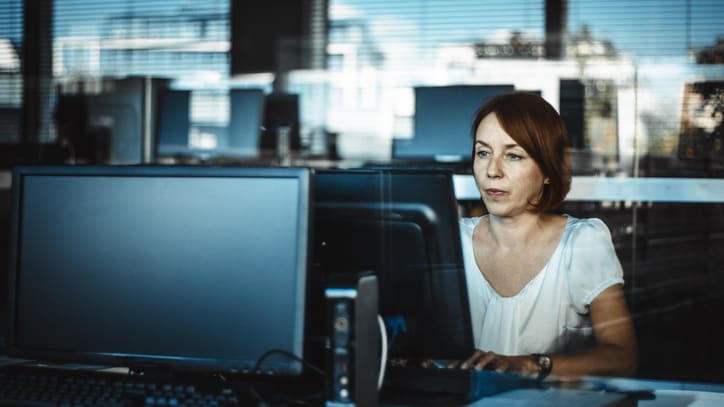 A woman is sitting in front of a computer screen.