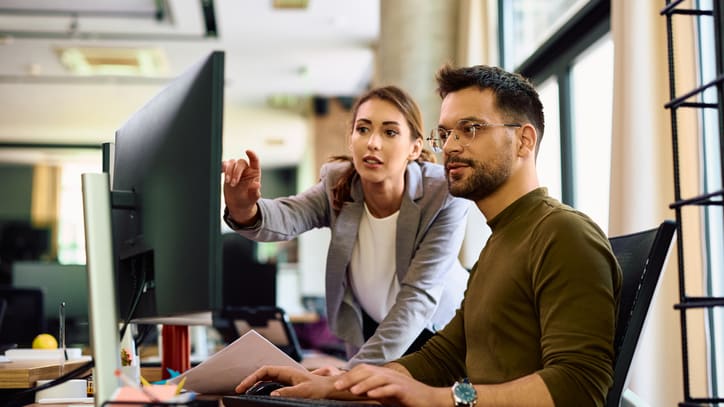 Two people working on a computer in an office.