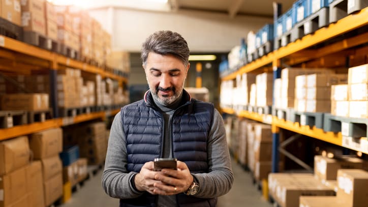 A man in a warehouse looking at his phone.