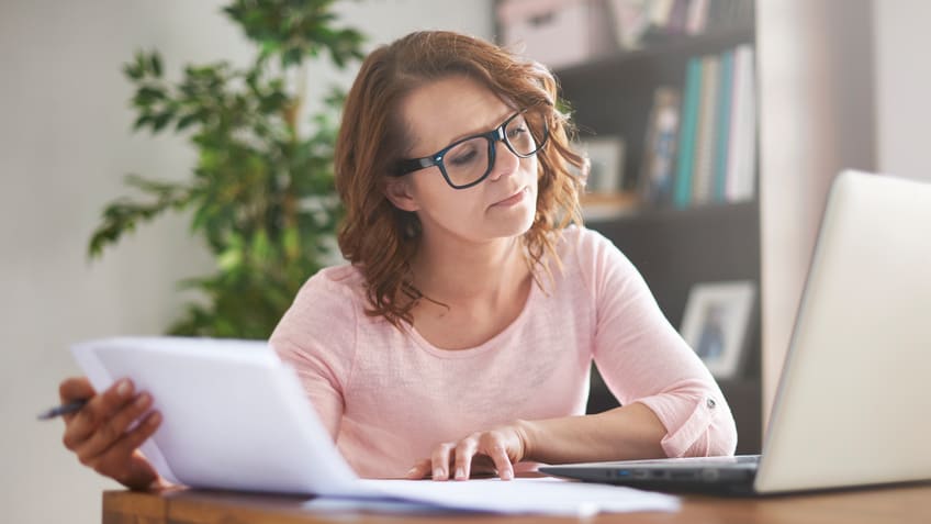 A woman sitting at a desk with a laptop and papers.